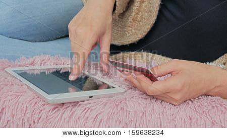 Young woman buying goods from the internet and entering number security code from credit card on digital tablet. Online, technology and internet concept.