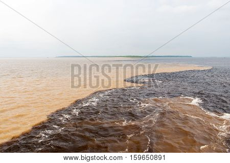 water meeting in brazil -amazon river with rio del negro clean and dirty river water with different streams