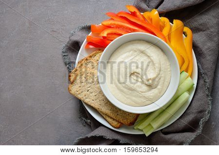 White bean hummus served with fresh vegetable sticks and whole grain crackers view from above space for a text