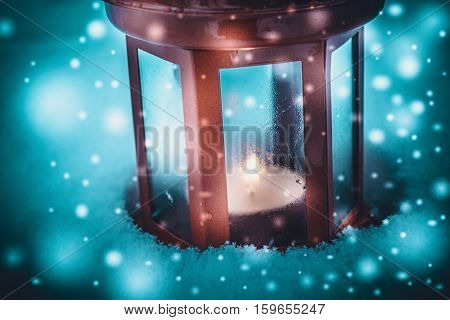 Red candle lantern with candle in snow during snowfall. Christmas Winter New Year background Scenery