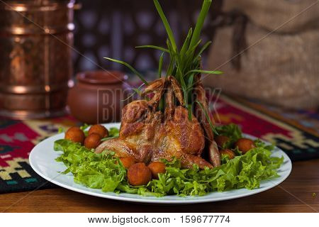 Chicken Tabaka With Potatoes And Lettuce On A White Plate