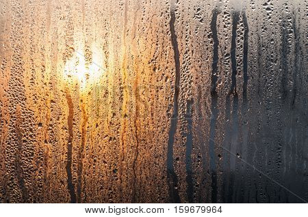Water drops on glass with sunrise background. Abstract texture.