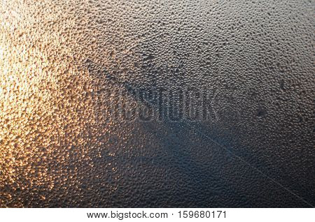 Rain drops on glass at sunset with trees silhouette background