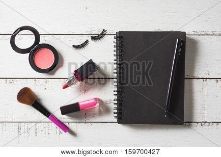 Blank notebook with Various make-up products and cosmetics on wooden table Top view