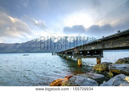 Wooden jetty with mountain at Glenorchy lake New Zealand.