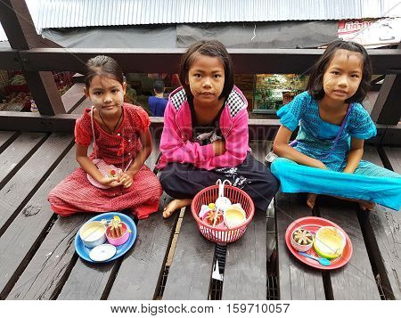 KANCHANABURI THAILAND - NOVEMBER 25: unidentified Burmese girls preparing thanaka powder for traveler at the old wooden Mon Bridge in Sangkhla Buri on November 25 2016 in Kanchanaburi Thailand