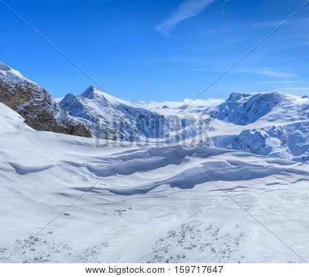 View from Mt. Titlis in Switzerland in winter, some snowflakes in the air over blue sky. Titlis is a mountain located on the border between the Swiss Cantons of Obwalden and Bern.