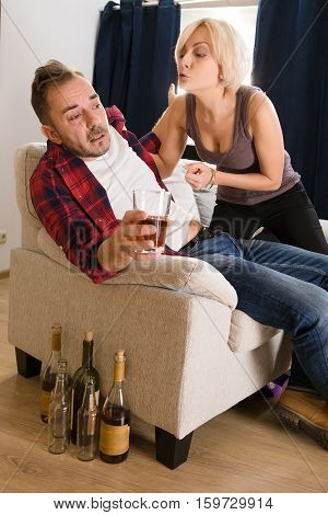 Couple man and woman having conflict while spending free time at home atmosphere. Blond wife screaming at her husband drunker. Alcohol concept.