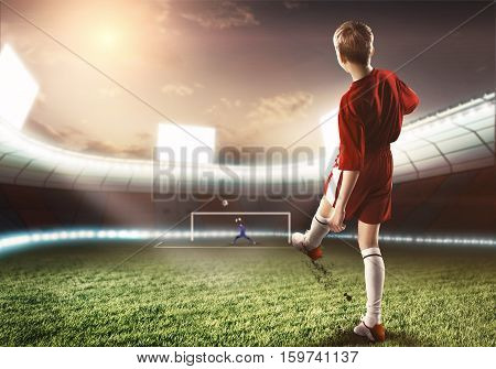 Kid boy football player on stadium kicking ball to gates
