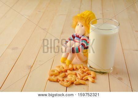 Girl dolls sitting beside glass milk and cookies are placed in front.