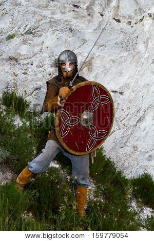 Knight on a rock with a sword against blue cloudy sky