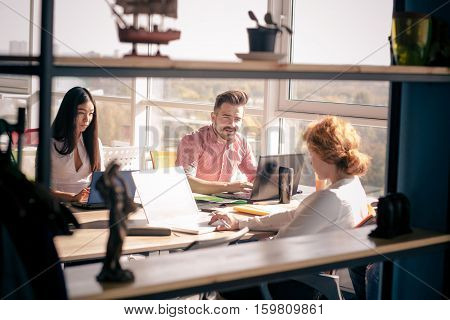 Business people working on laptop computer and discussing their positions concening new business strategy in board room in office. Freelance concept.