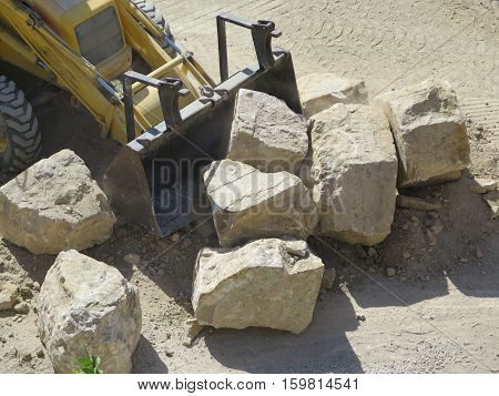 Backhoe loader moving rocks for new retaining wall