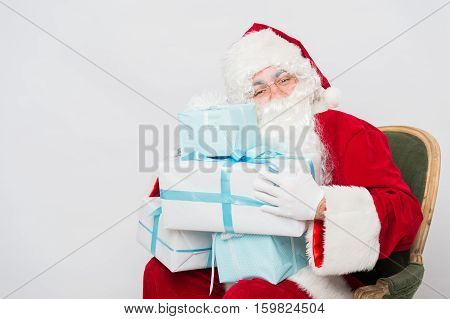 Photo of happy Santa Claus with giftboxes looking at them.