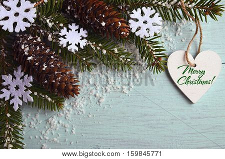 Merry Christmas greeting card.Decorative snowflakes,fir cones,heart and snowy fir tree branch on light blue background.Christmas decoration.Selective focus.