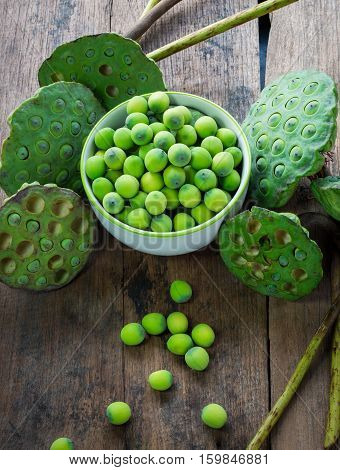 Lotus Seeds In White Bowl And Calyx On Wood Background