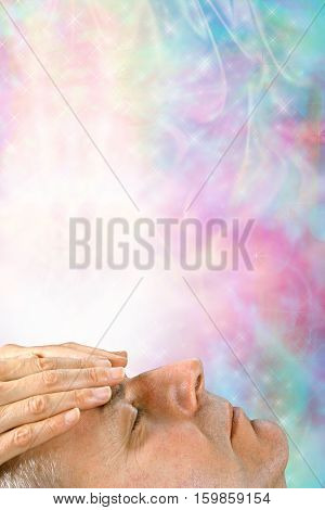 Receiving healing energy through crown chakra - male with eyes closed with female hands hovering over his forehead and a shaft of white light coming down on a colorful ethereal energy background