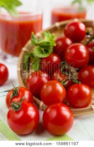 Tomato juice in a glass with a cherry and mint on a light background