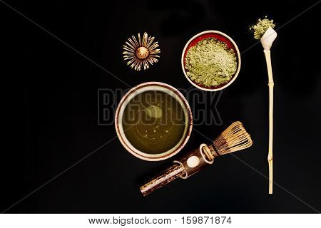 Chasen - special bamboo whisk, spoon for matcha tea and beverage with apetite foam. Black background. Photo made in flat lay style. Focus is on matcha foam.