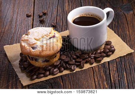 Cup of hot coffee and muffin on dark wooden table
