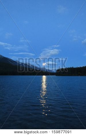Moonrise with clouds over a lake. Banff, Canada.