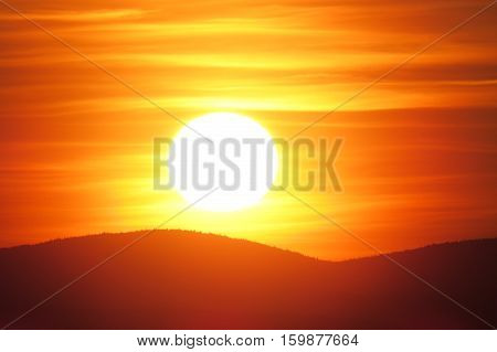 Bright orange sunset above the mountains. Quebec, Canada.