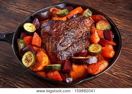 Oven baked Juicy pork loin with vegetables in griddle rustic pan.