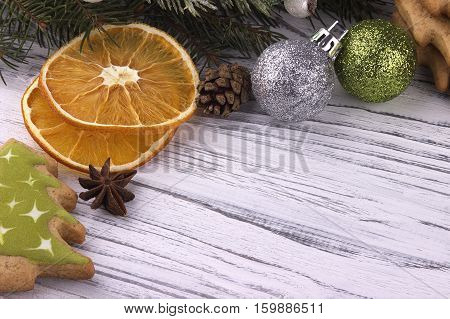 Christmas Xmas New Year holiday Background with dried oranges cookies star anise cinnamon cones natural fir branches green and silver balls on white wooden table