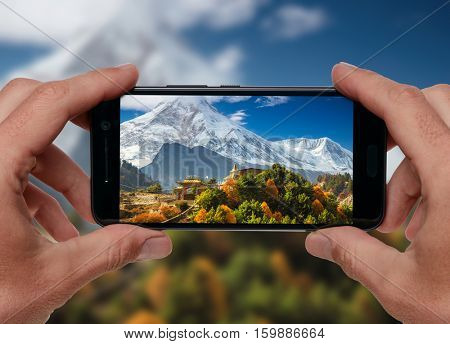 Travel concept. Tourist making photo of Himalayas mountain landscape. Buddhist monastery and Manaslu mount in Himalayas, Nepal.