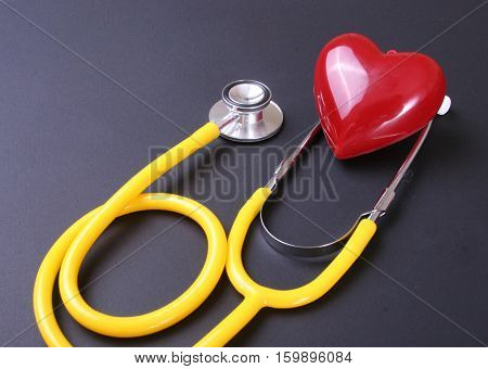 Red heart and a stethoscope on desc.
