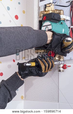 plumber installs household wall electric heating boiler