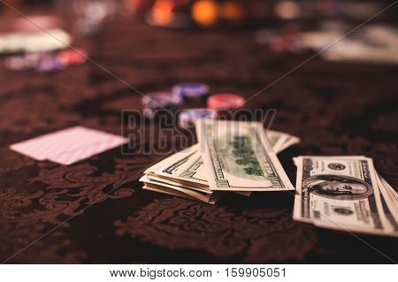 A close-up vibrant image of multicolored casino table with roulette in motion, with the hand of croupier, and a group of gambling rich wealthy people in the background