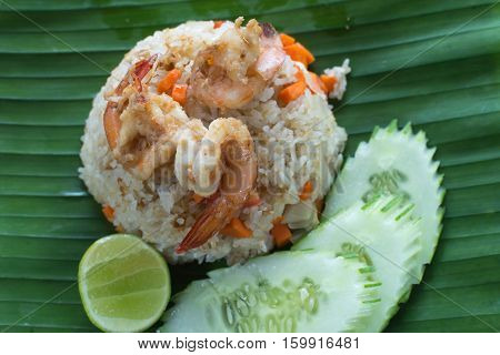A simple menu of stir-fried rice with prawns and vegetables served on a banana leaf.