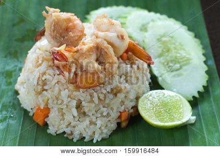 A simple menu of stir-fried rice with prawns and vegetables served on a banana leaf.