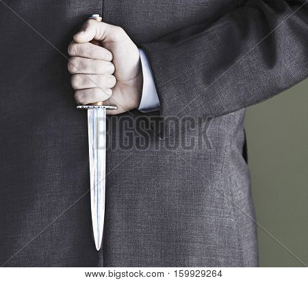 Closeup midsection of businessman holding knife against black background