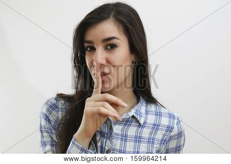 Young girl making silence gesture pst shh