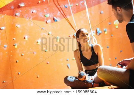 Interesting leisure time. Amused young active couple sittiing together in a climbing gym after training.and enjoying their hobby.