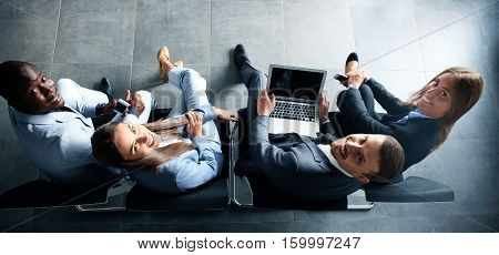 Group of attractive young bussinespeople sitting on the chairs using a laptop Tablet PC smart phones smiling