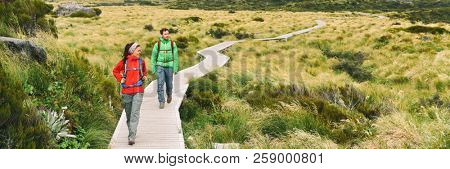 Hikers people hiking walking on Hooker Valley Track in summer lifestyle. Couple on travel holiday adventure. Banner panorama. New Zealand trampers backpacking on Mount Cook / Aoraki Hooker Valley.