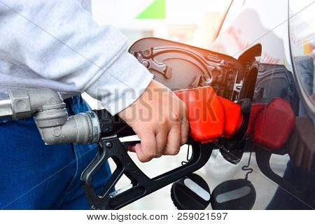 Man Holding Red Fuelling Nozzle And Pumping Gasoline Fuel Fill In Car At Gas Station, Car Fuels Or T