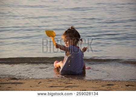 Little Girl Plays On The Sand Beach With Whater Splash, Waves
