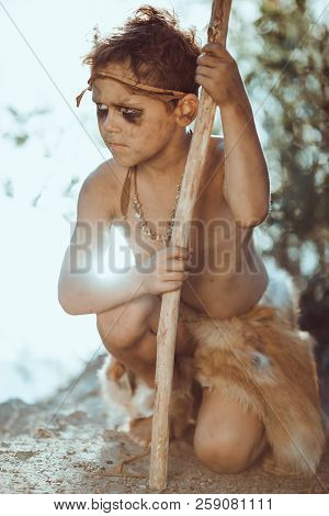 Cute Caveman, Manly Boy With Staff Hunting. Prehistoric Tribal Boy Outdoors On Nature. Young Shaggy 