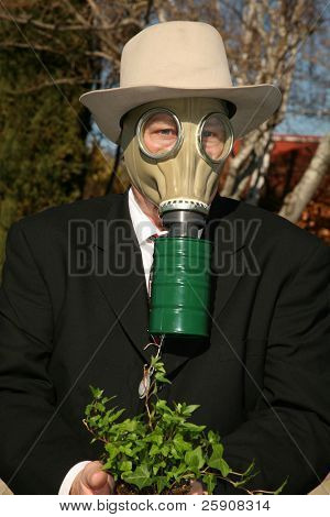 素敵なスーツと、ガスマスクで環境に優しいビジネス男 t を保存する緑の植物を保持します。