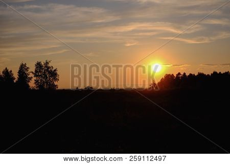Simple And Uncomplicated Landscape At Sunset In Orange Tones, In The Middle Plan You Can See The Tre