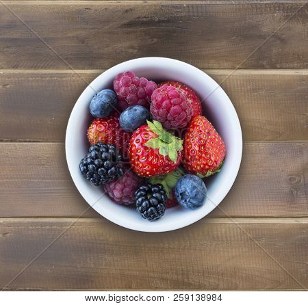 Top View. Fruits And Berries In Bowl On Wooden Background. Ripe Raspberries, Strawberries, Blackberr