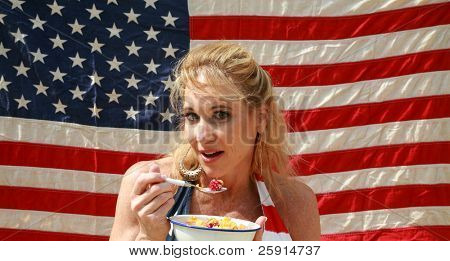 una donna si gode una ciotola di cereali con latte e lamponi una mattina davanti alla sua bandiera americana
