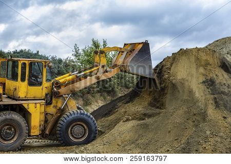 Wheel Loader Excavator With Backhoe Unloading Sand At Eathmoving Works In Construction Site Quarry