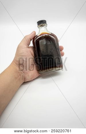 Hand Holding The Cold Brew Coffee In Glass Bottle With Black Cap Isolated On White Background