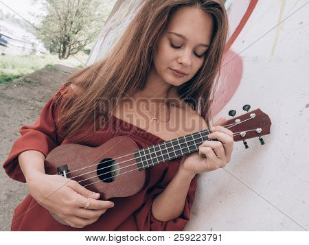 Young woman playing on ukulele