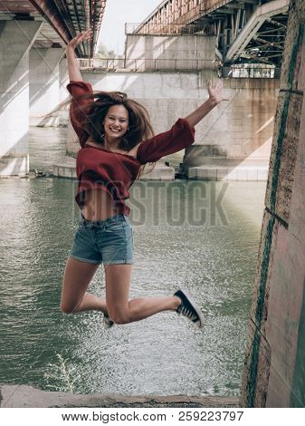 Happy woman jumping under the bridge